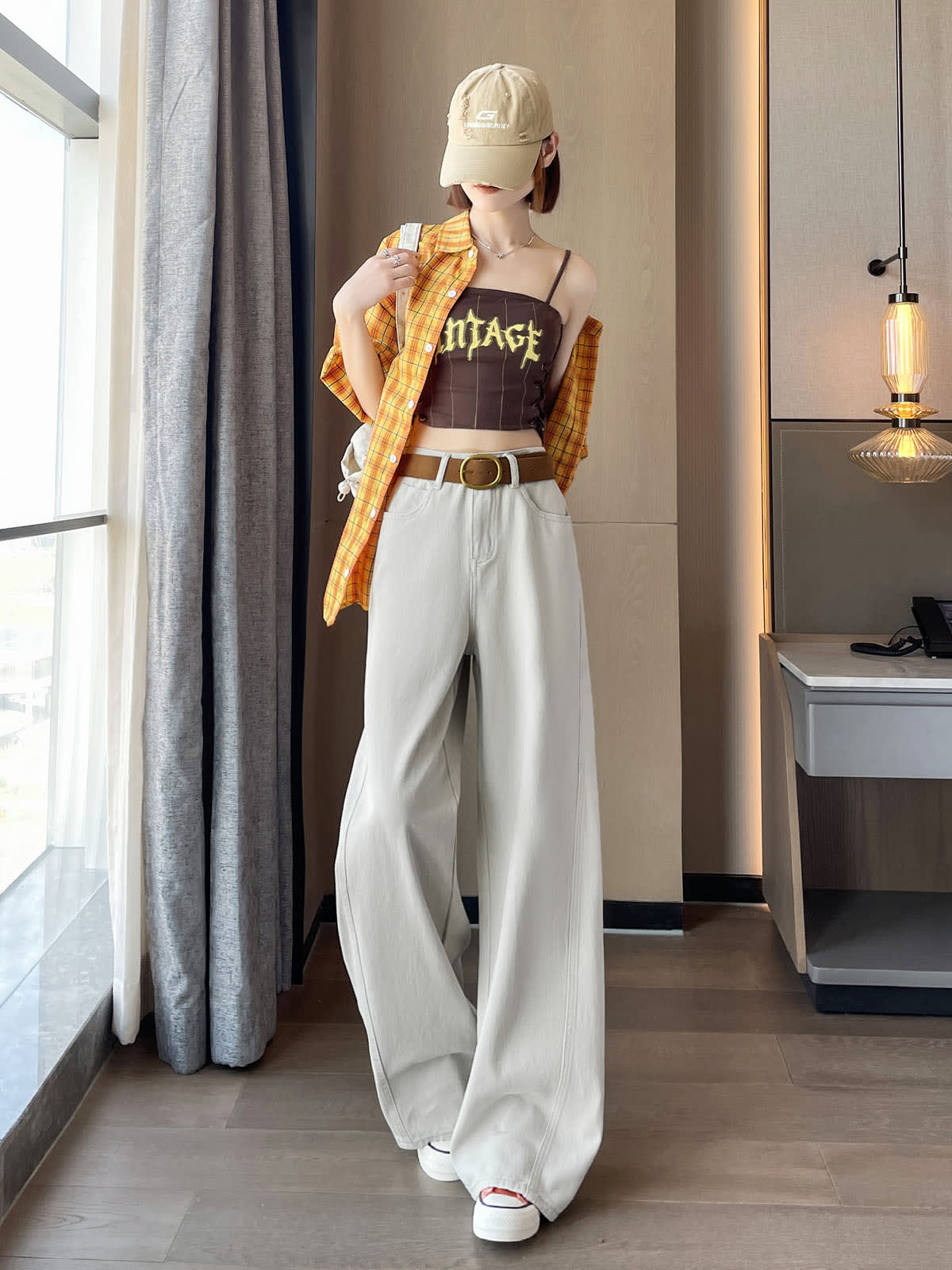 YEEYEEWang 토프 그레이 대드 커브드 진, 아시안핏, 한쪽 어깨에서 체크 셔츠를 내린 정면 전신 스탠딩 포즈, 베이지 캡 착용.