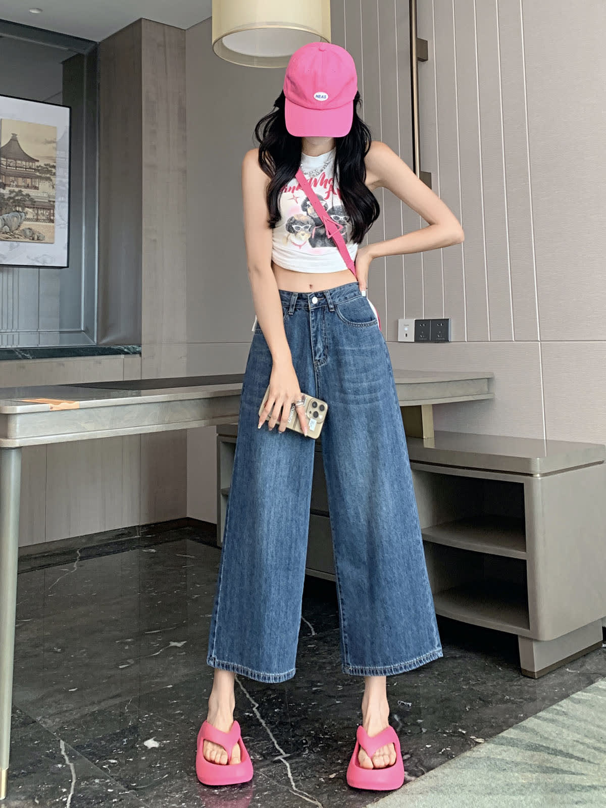YEEYEEWang 빈티지 블루 와이드레그 진, 아시안핏, 전신 정면 서서 한 손은 허리에 올리고 폰을 들고, 핑크 캡과 크로스백.