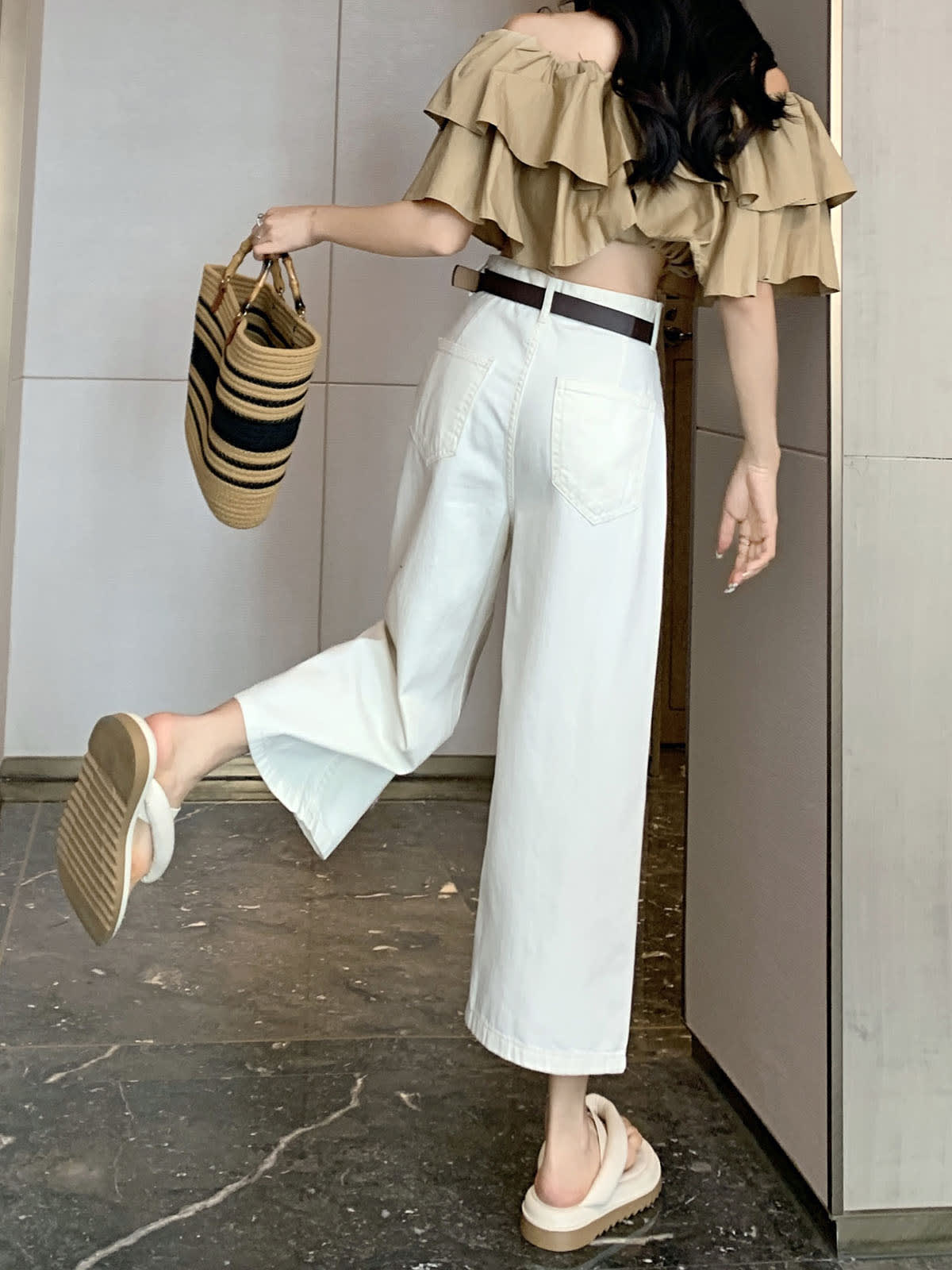 YEEYEEWang 아이보리 와이드레그 진, 아시안핏, 한 다리를 뒤로 든 전신 후면 컷, 스트로 토트와 브라운 벨트.