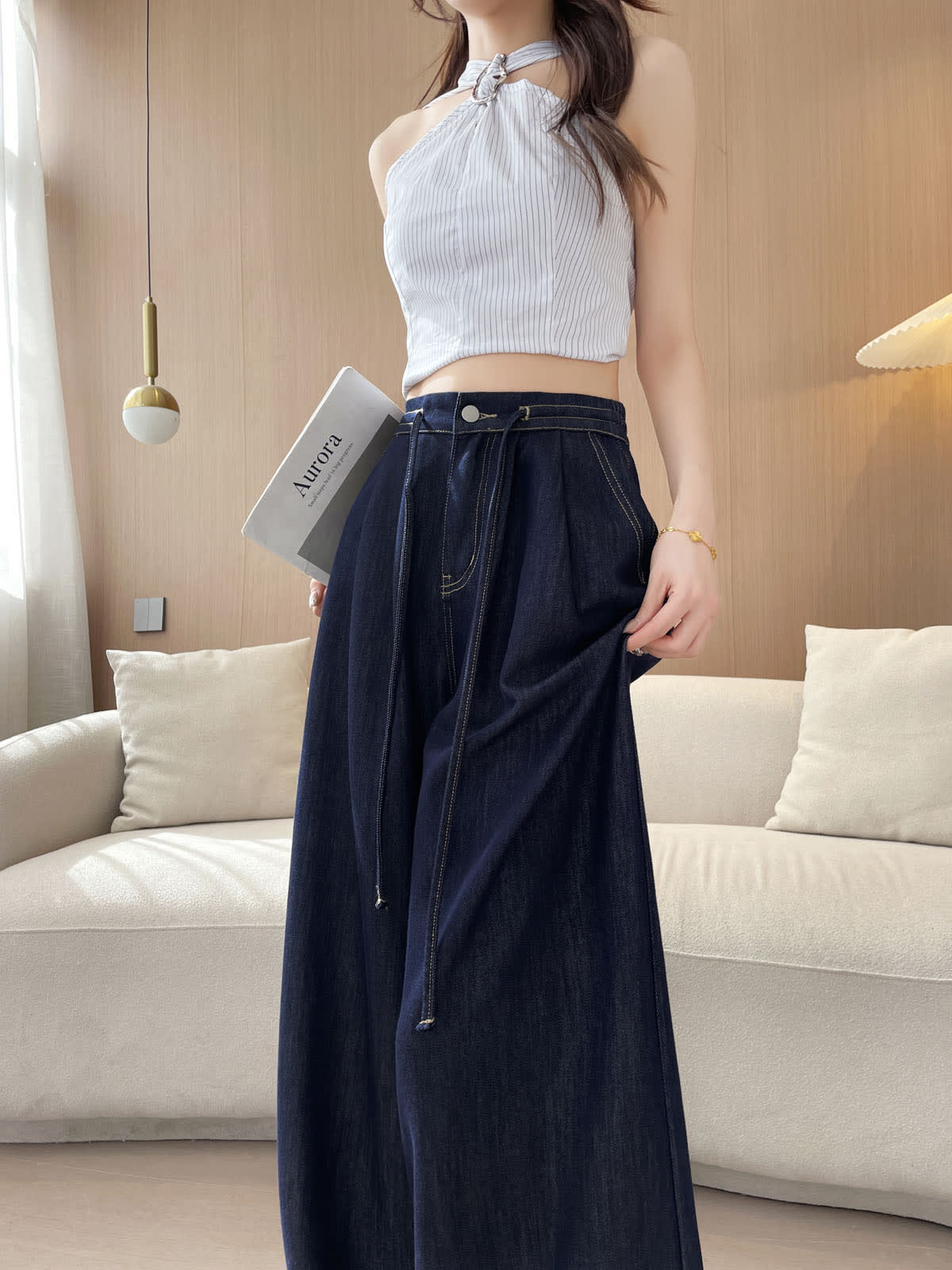 YEEYEEWang 데님 블루 와이드레그 진, 아시안핏, 정면 상반신 포즈, 한 손에 책, 드로스트링 허리와 실버 버튼, 플리츠 디테일.