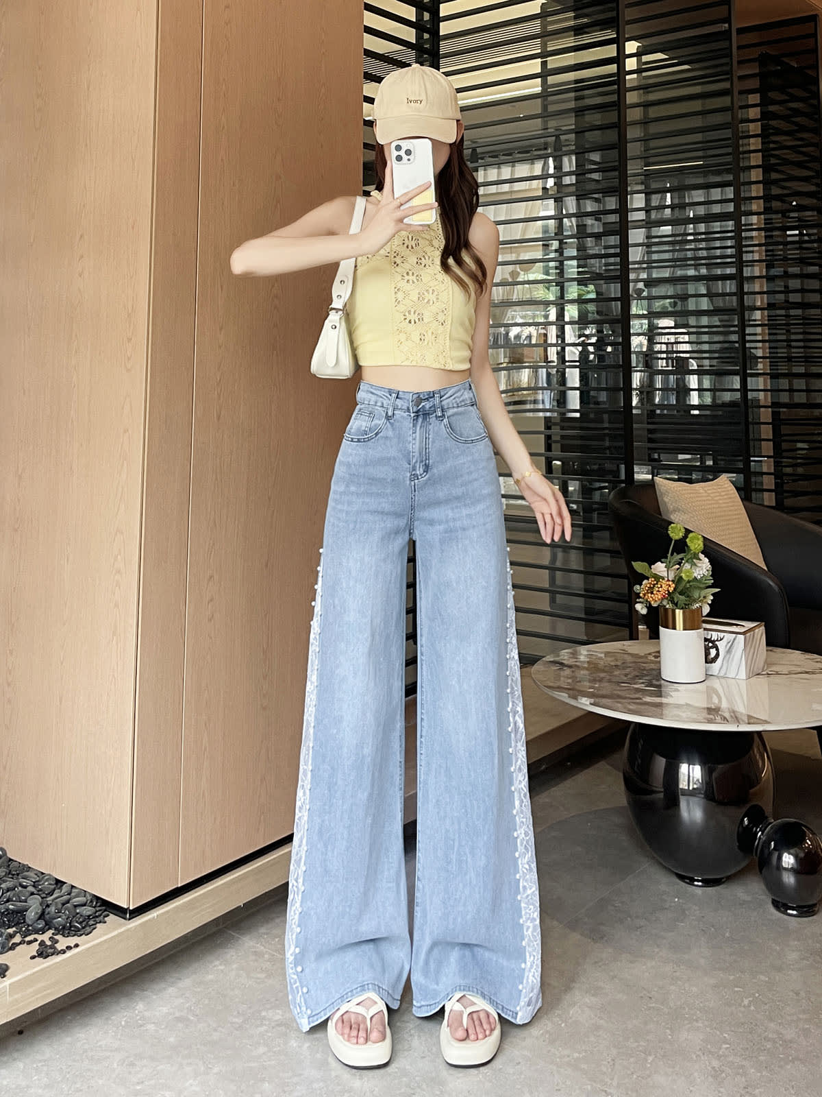YEEYEEWang 연청 와이드레그 진, 아시안핏, 얼굴 앞에 폰을 든 전신 정면 포즈, 옐로우 홀터넥에 화이트 백과 베이지 캡.