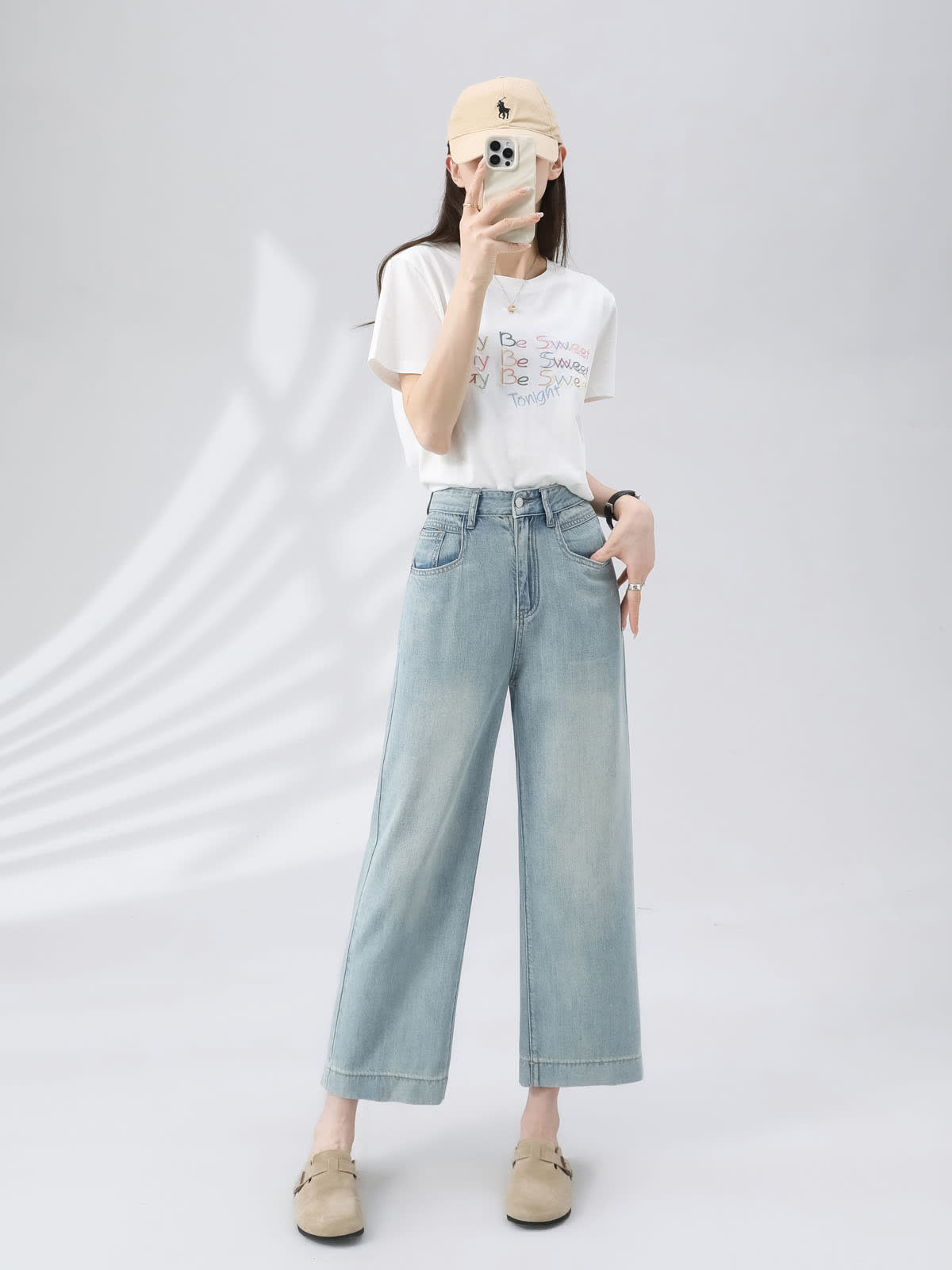 YEEYEEWang 라이트 블루 와이드 레그 진, 아시안핏, 전신 정면 포즈, 휴대폰을 얼굴 앞에 들고 다른 손은 주머니에, 베이지 캡.