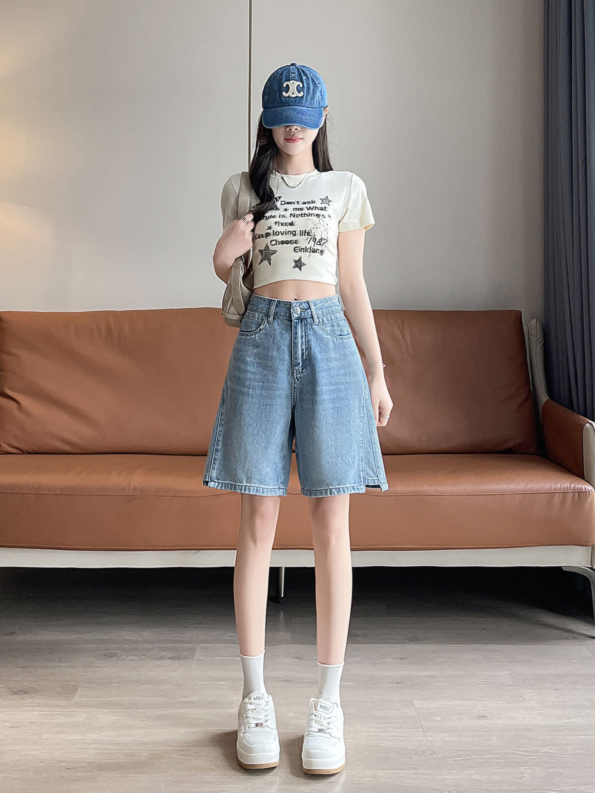 YEEYEEWang 블루 데님 버뮤다 쇼츠, 아시안핏, 전신 정면 선 자세, 숄더백 끈을 잡고 데님 캡과 화이트 스니커즈 코디.