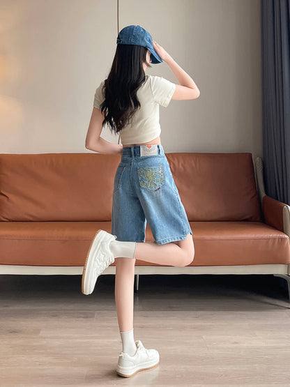 YEEYEEWang 블루 데님 버뮤다 쇼츠, 아시안핏, 전신 뒤쪽 3/4 각도, 한 다리를 뒤로 든 포즈, 손으로 캡 챙을 만지며 뒷주머니 자수가 보임.