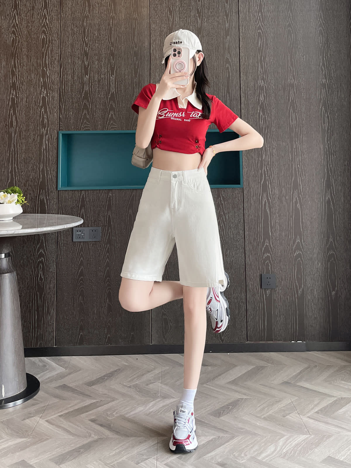 YEEYEEWang 화이트 데님 버뮤다 쇼츠, 아시안핏, 전신 정면 한쪽 다리 뒤로 차는 포즈, 얼굴 앞 폰, 한 손은 허리에.
