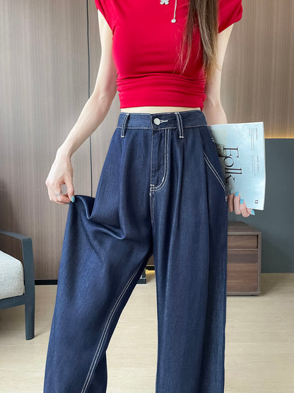 YEEYEEWang 데님 블루 와이드 레그 진, 아시안핏, 허리 아래 정면, 한 손으로 원단을 잡아 드레이프를 보여주고 다른 손에 잡지를 든 모습.